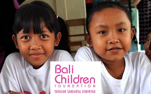 Two smiling girls with the Bali Children Foundation logo