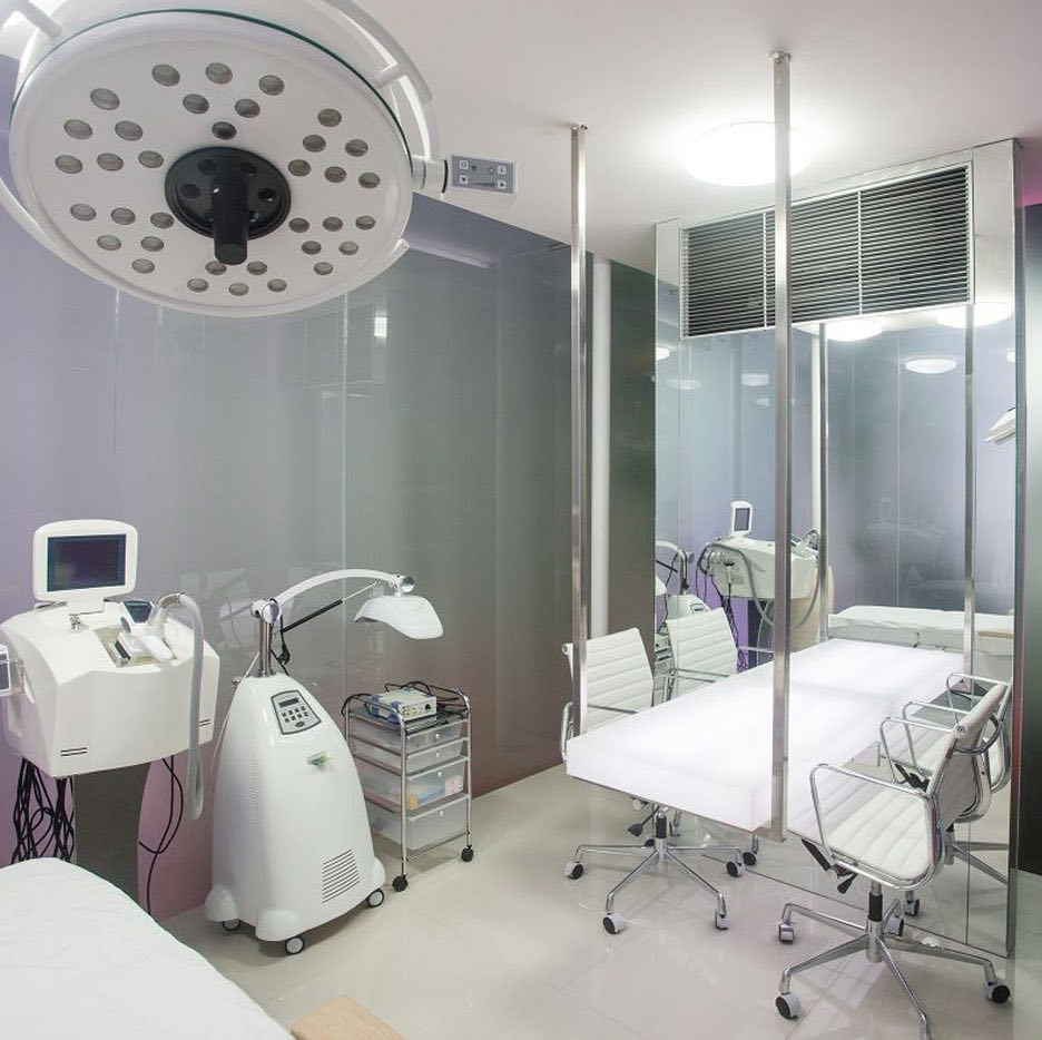 A Cocoon consultation room: a treatment bed under a surgical light, beside medical devices and glass walls