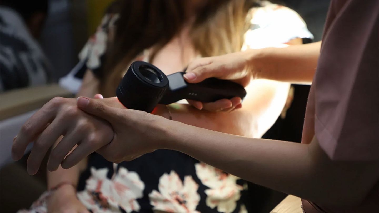 A doctor examining a guest’s skin through a dermatoscope