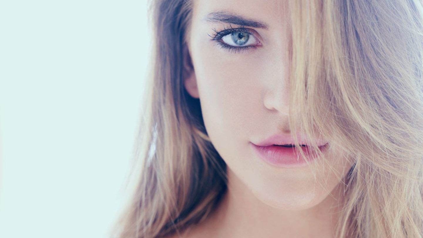 A woman with light hair across one eye, her skin clear and smooth
