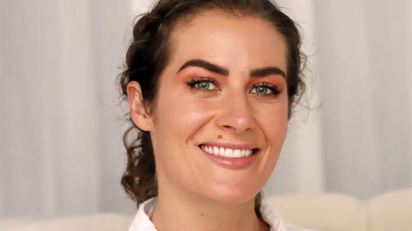 A smiling woman with dark hair and clear, even skin