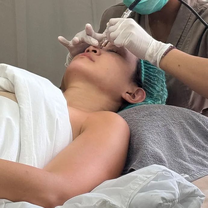A Cocoon therapist in a mask and gloves giving a guest a facial treatment at the Canggu clinic