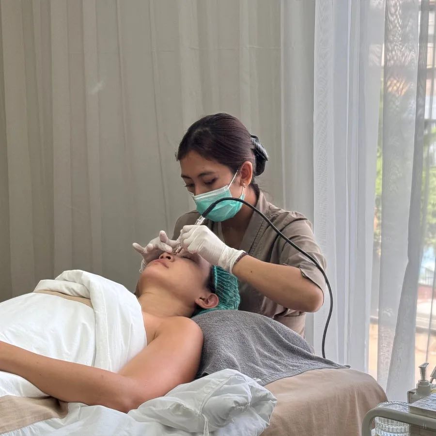 A Cocoon therapist in a mask and gloves giving a guest a facial treatment at the Canggu clinic