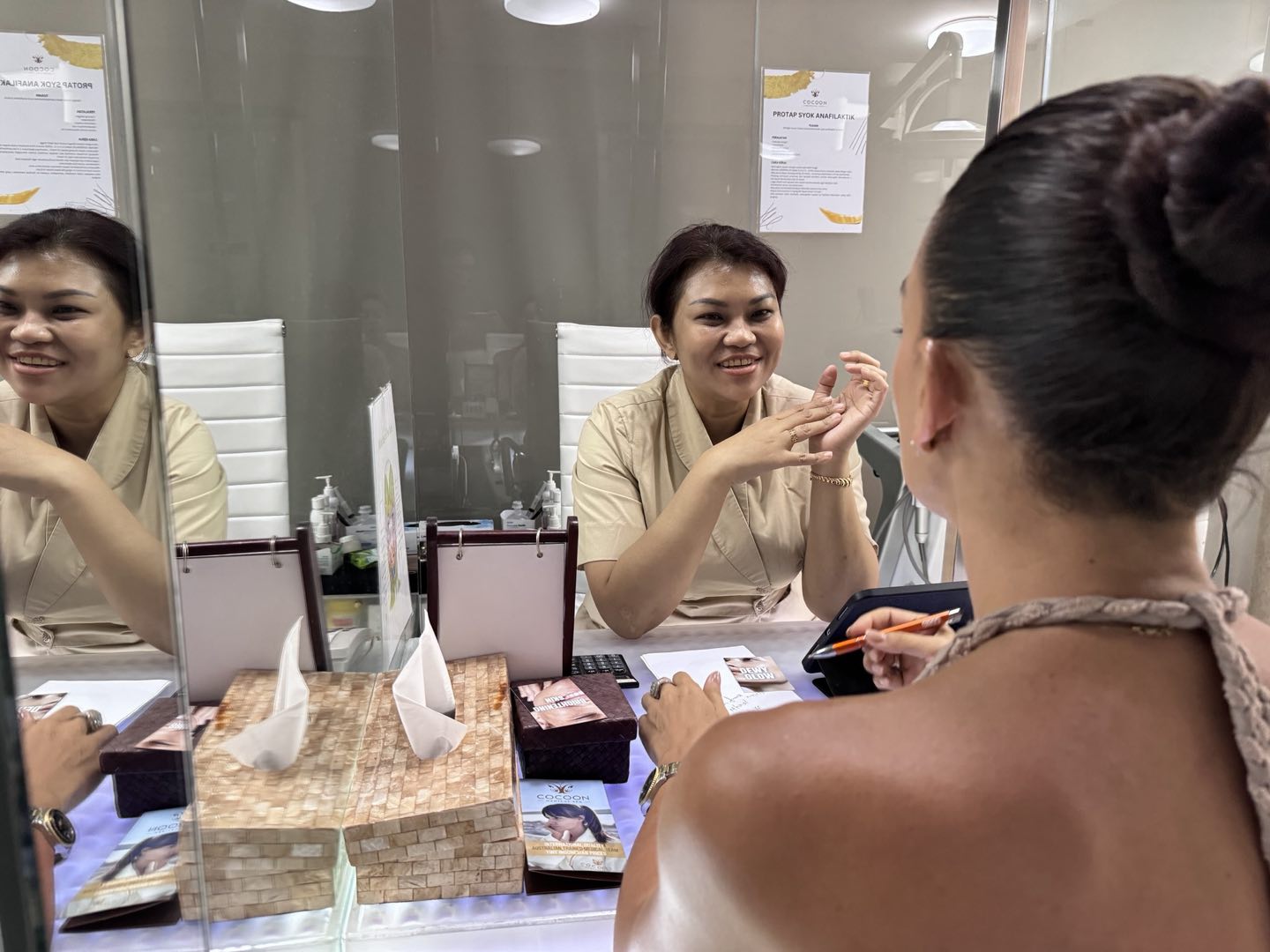 A guest at the Cocoon consultation desk, the clinic’s certificates framed on the wall behind
