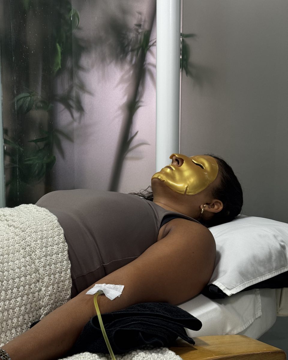 A guest resting in a gold face mask while a drip runs