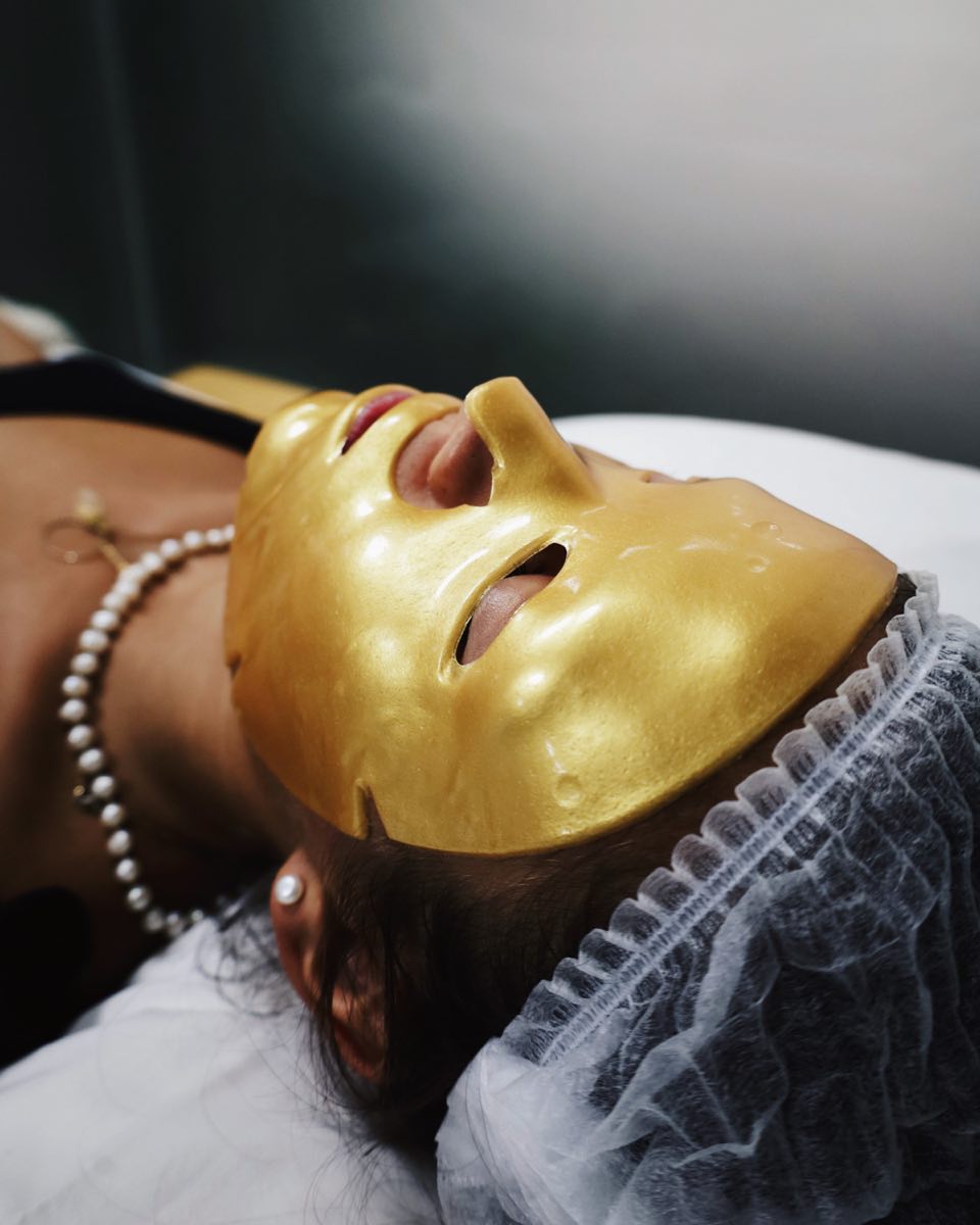A guest resting in a gold collagen mask