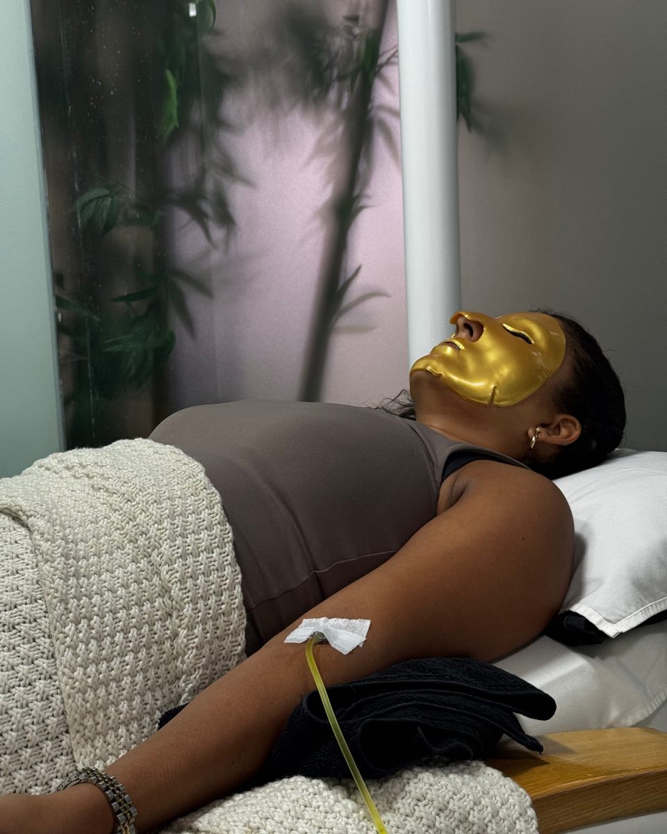 A guest resting in a gold mask, a drip line taped inside her elbow