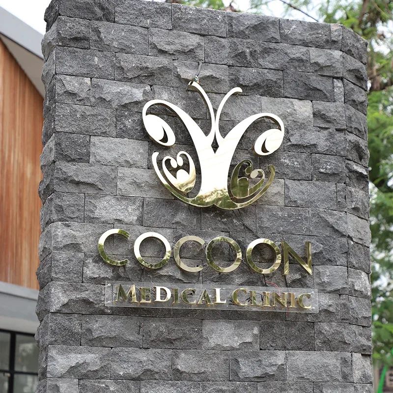 The Cocoon Medical Clinic sign in gold on a grey stone wall