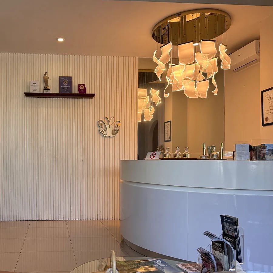 The Canggu reception: a curved white desk beneath a sculptural chandelier