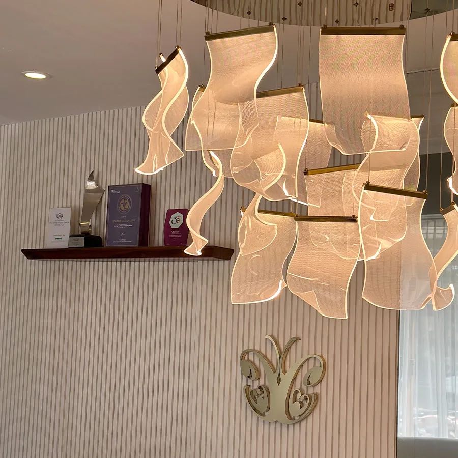 Sculptural pendant lights and the gold butterfly logo on a pale ribbed wall