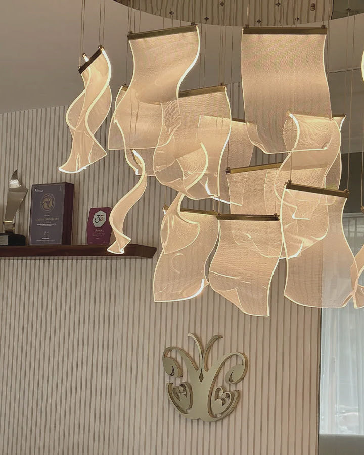 Folded light panels of the chandelier at Cocoon Canggu, above the ribbed wall and the gold butterfly