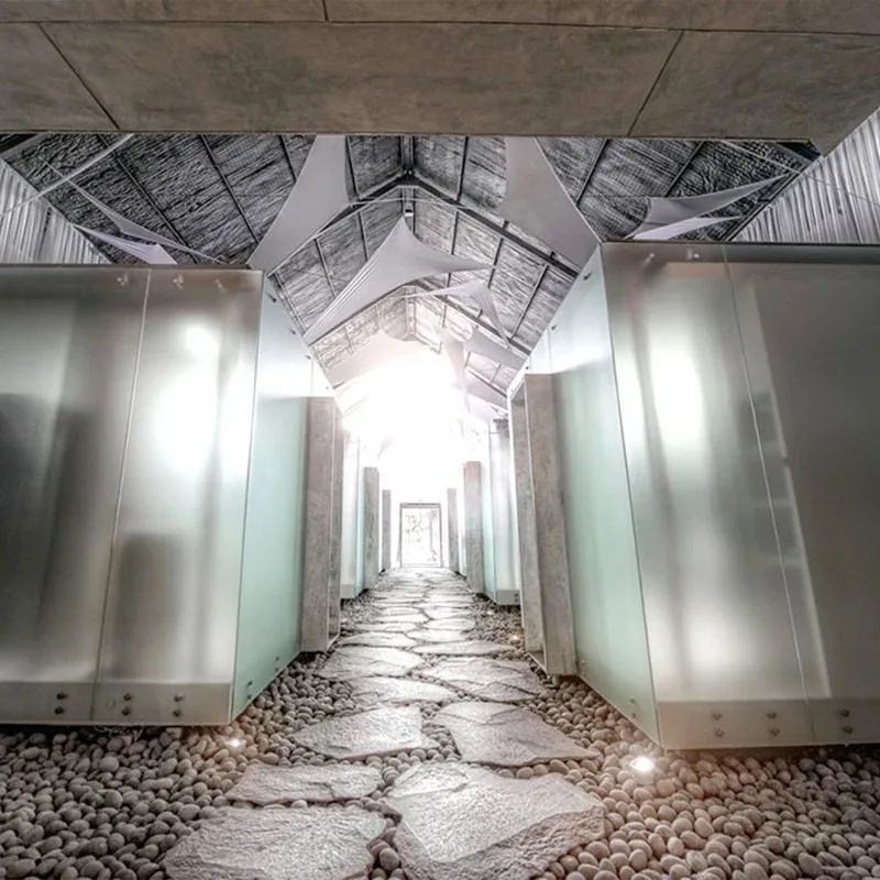 Stepping stones over river pebbles between frosted glass treatment rooms under a timber roof