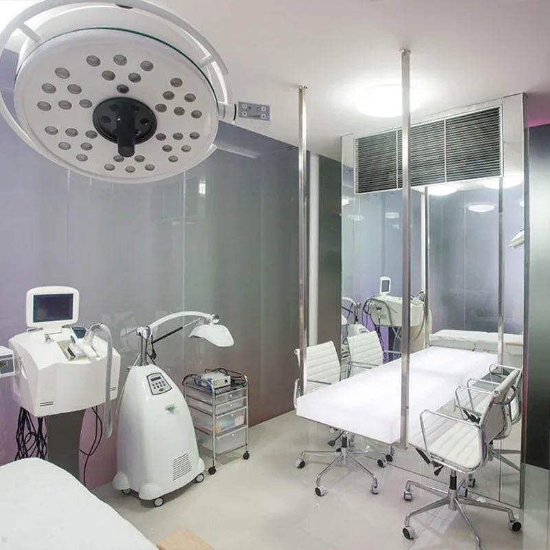 A bright Cocoon Legian treatment room with a medical lamp, laser devices and white leather chairs