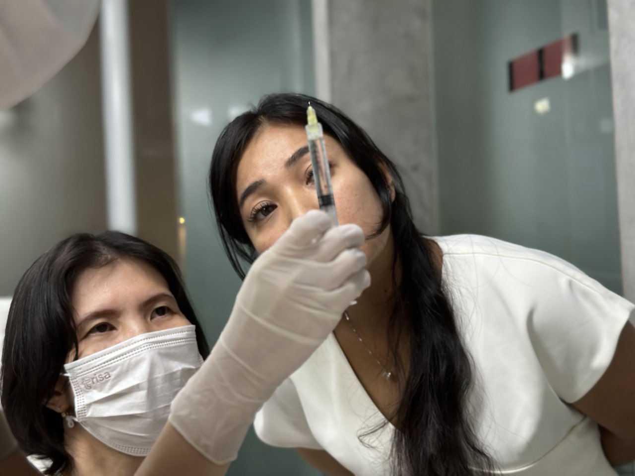 A Cocoon doctor checking a skin booster syringe before treatment, with a colleague alongside