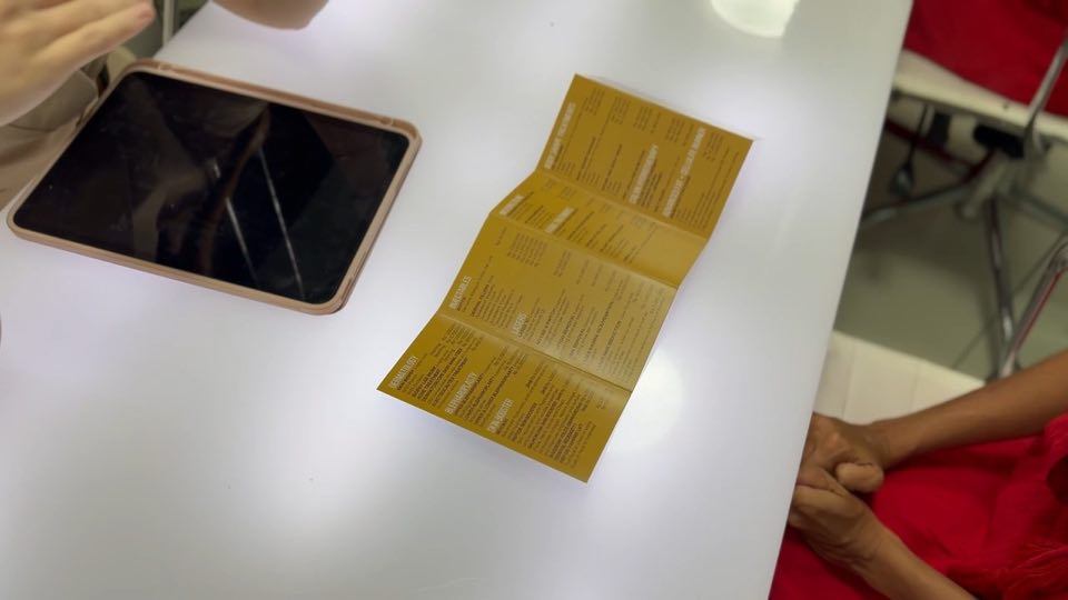 A Cocoon treatment menu open on the reception desk beside a guest’s phone