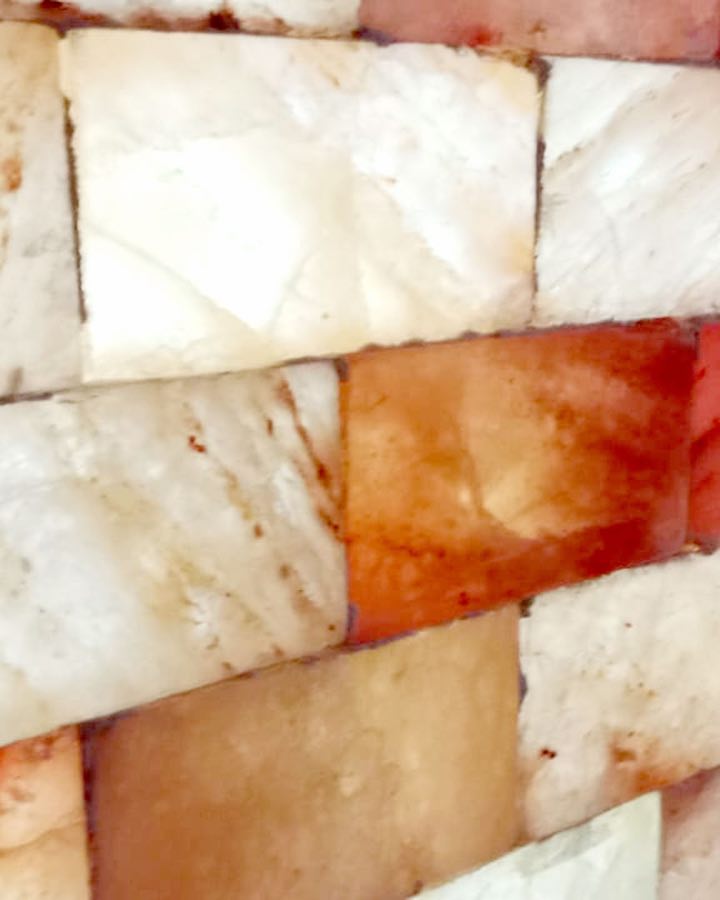 Himalayan salt bricks in the salt room wall, glowing white and rust red from behind