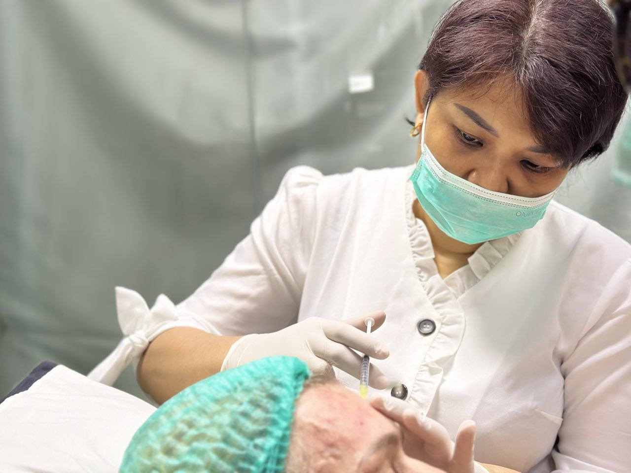 A Cocoon doctor, gloved and masked, placing a precise Botox® injection in a client’s forehead
